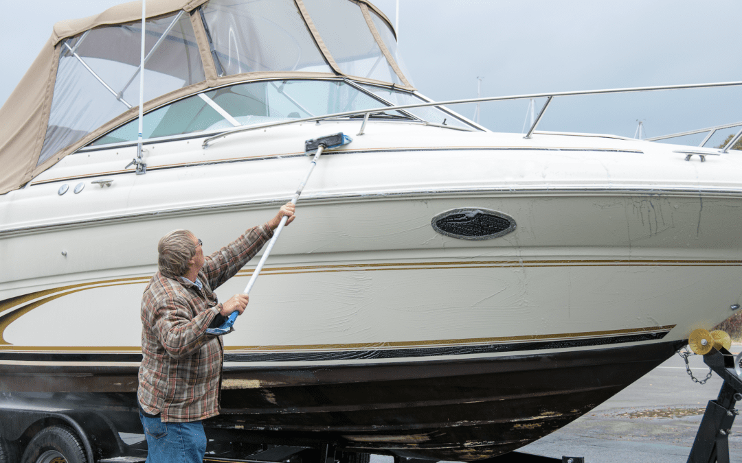 Guy cleaning tall boat with scrub brush on extension rod.