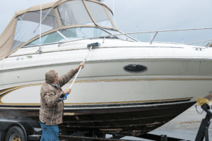 Guy washing large boat with brush on extension rod
