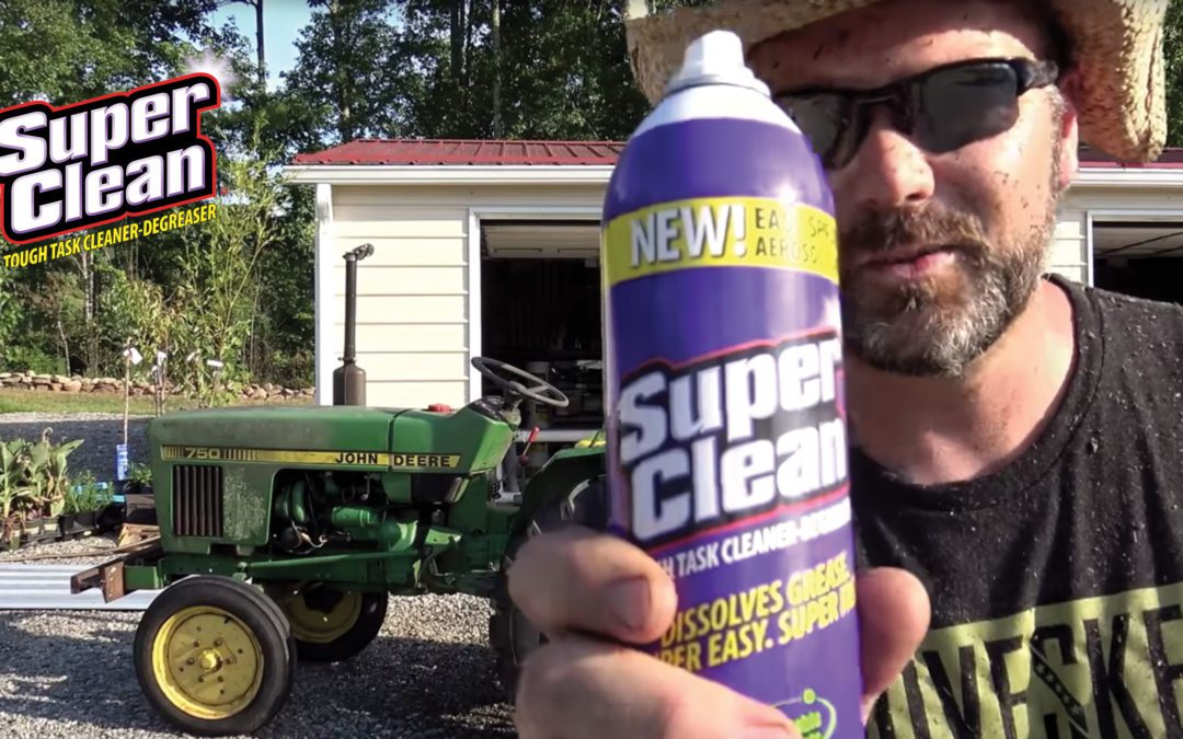 Farmer holding aerosol can in front of tractor and garage