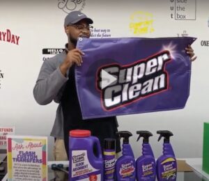 Man holding Super Clean banner with product in front on table